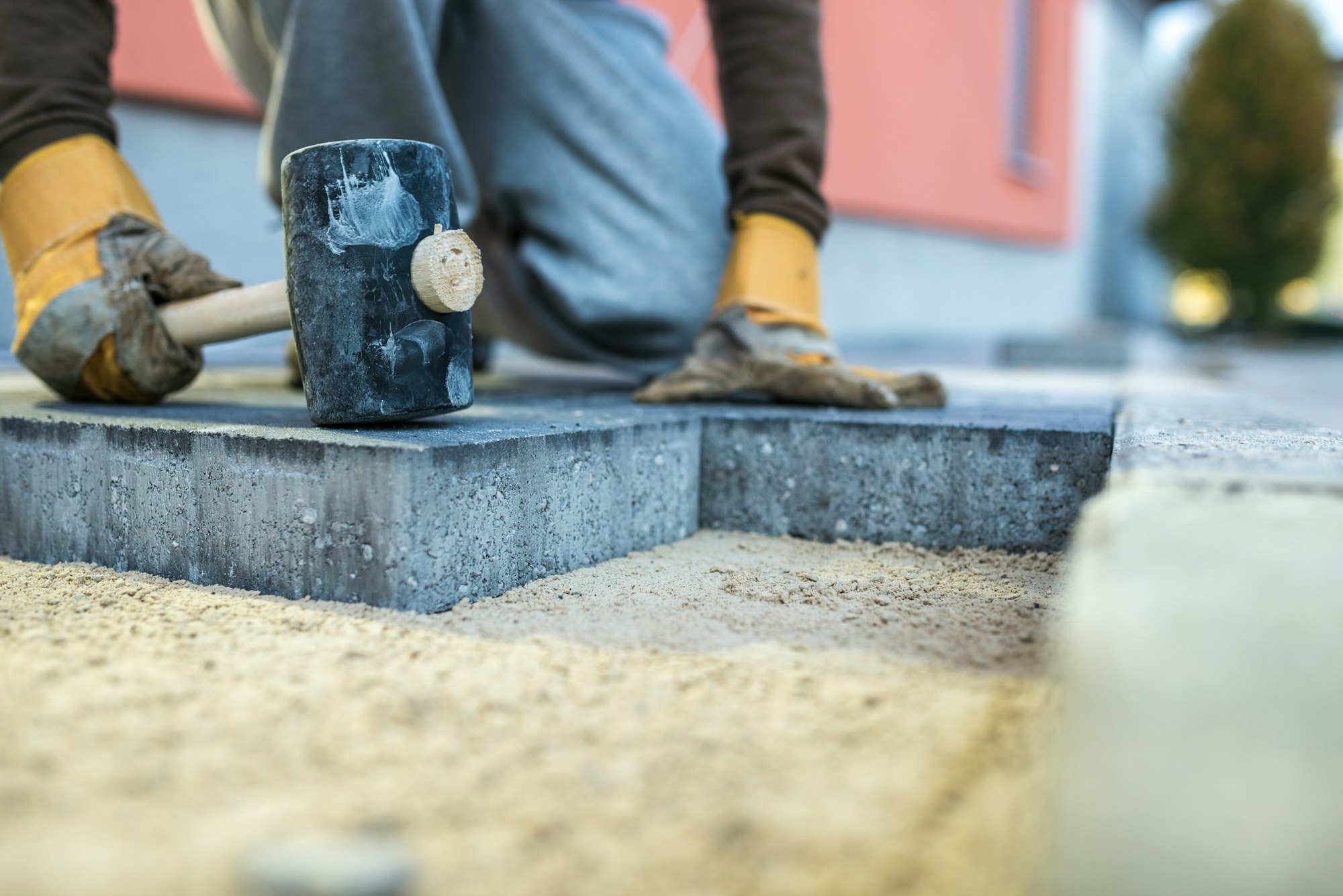 Workman tamping down a new paving brick